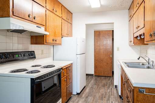 A kitchen with wooden cabinets and a white stove top oven. Fargo, ND Islander Apartments