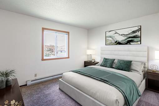 A bedroom with a large bed and a painting on the wall. Fargo, ND Summerfield Apartments