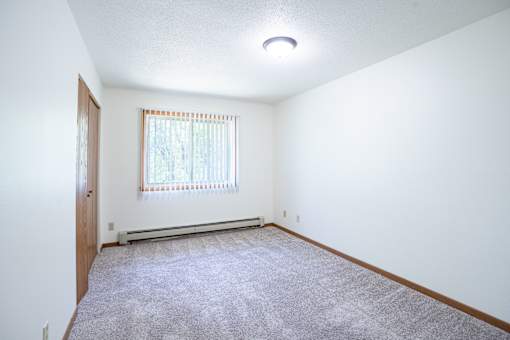 A room with a window and a carpeted floor. Grand Forks, ND Columbia West Apartments