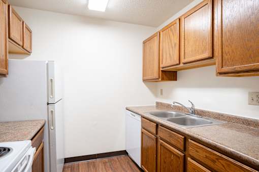A kitchen with a white refrigerator and brown cabinets. Fargo, ND Summerfield Apartments