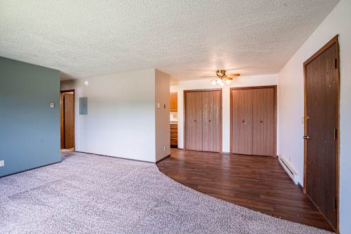 A room with a carpeted floor and wooden doors. Fargo, ND Summerfield Apartments