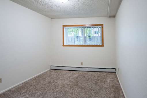 A room with a window and carpeted floor. Fargo, ND Park Terrace Apartments