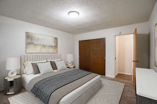 A bedroom with a large bed and a painting on the wall. Fargo, ND Park Terrace Apartments