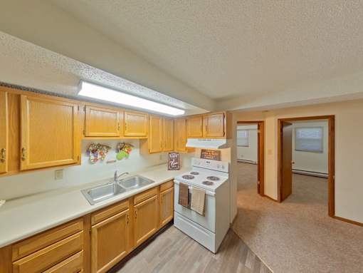 A kitchen with wooden cabinets and a white stove top oven.