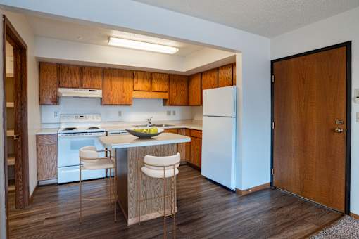 A kitchen with wooden cabinets and a white fridge. West Fargo, ND Clearview Apartments