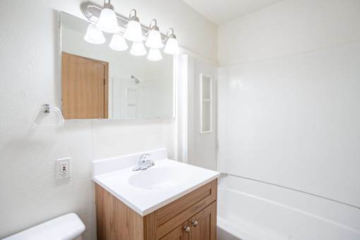 A white sink in a wooden cabinet under a mirror. West Fargo, ND Sheyenne Terrace Townhomes