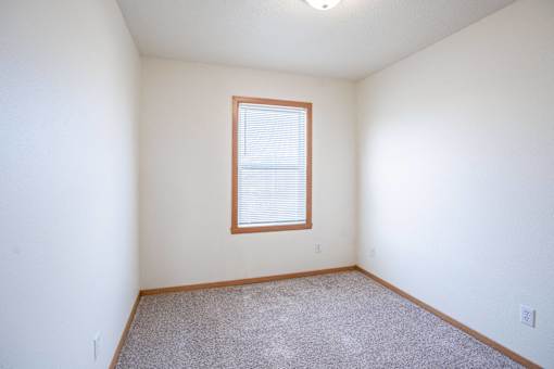 A room with a window and carpeted floor. West Fargo, ND Sheyenne Terrace Townhomes