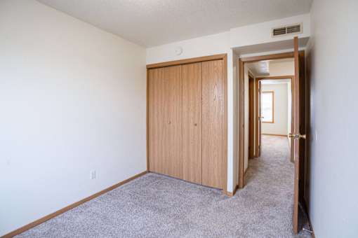 A room with a carpeted floor and a wooden door. West Fargo, ND Sheyenne Terrace Townhomes