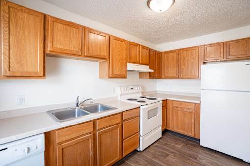 A kitchen with wooden cabinets and white appliances. West Fargo, ND Sheyenne Terrace Townhomes