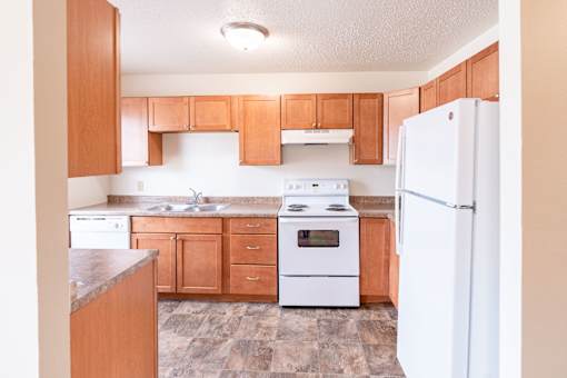 A kitchen with wooden cabinets and white appliances. West Fargo, ND Sheyenne Terrace Townhomes