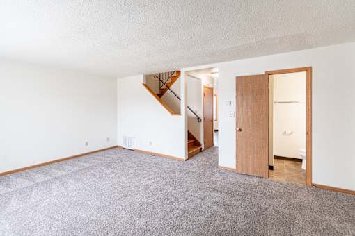 A room with a carpeted floor and a staircase. West Fargo, ND Sheyenne Terrace Townhomes