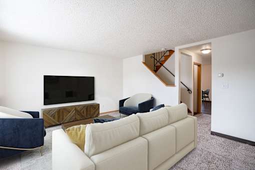 A living room with a white couch and a television. West Fargo, ND Sheyenne Terrace Townhomes