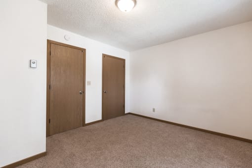 Bismarck, ND Arbor 400 Apartments.  A bedroom with a carpeted floor and a wooden door