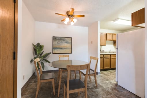 Bismarck, ND Arbor apartments. a dining area with a table and chairs and a kitchen in the background