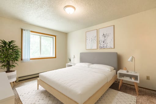 Bismarck, ND Brandon Apartments. The room showcases a comfortable bed with neatly arranged bedding and a calm ambiance. Soft lighting adds to the peaceful atmosphere, while a window allows natural light to fill the space. It's a tranquil retreat for rest and relaxation.