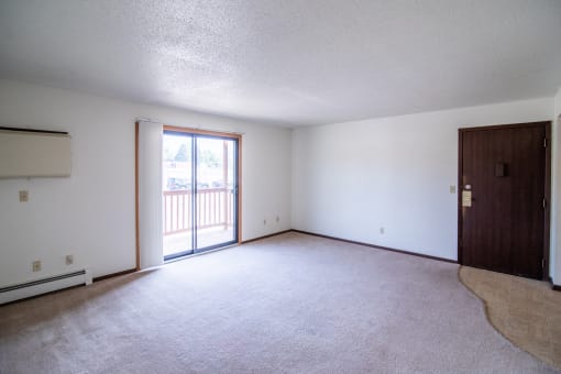A living room with a door to a balcony. Bismarck, ND Eastbrook Apartments.