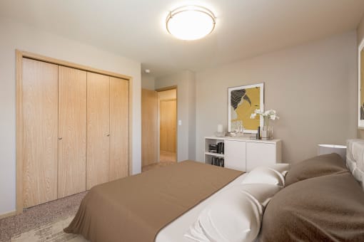 Bismarck, ND Stonefield Townhomes. The room features a comfortable bed, stylish furnishings, and a warm color palette, creating a relaxing atmosphere. The wardrobe provides storage space for the small room.