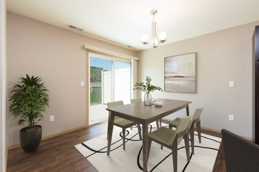 Bismarck, ND Stonefield Townhomes. The space features a well-appointed dining table with 4 chairs, modern kitchen appliances, and tasteful decor. Bright natural light fills the room from the glass sliding door.