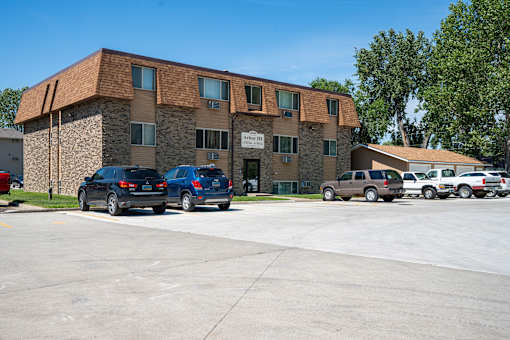 A parking lot in front of a building with cars parked. Bismarck, ND Arbor 406 Apartments