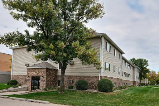 an apartment building with a tree in front of it. Fargo, ND Brownstone Apartments