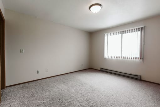 Grand Forks, ND Carling Manor Apartments. a bedroom with a large window and beige carpet