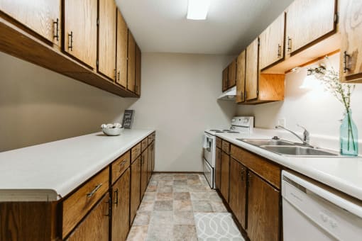 Grand Forks, ND Carling Manor Apartments. a kitchen with wooden cabinets and a white counter top