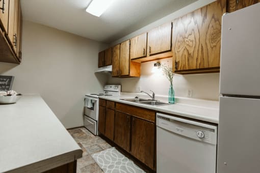 Grand Forks, ND Carling Manor Apartments.  a kitchen with white appliances and wooden cabinets