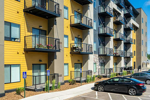 an apartment with balconies and cars parked in front of them. Circle Pines, MN Lexington Lofts