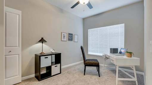 a bedroom with a desk and a chair and a window. Circle Pines, MN Lexington Lofts