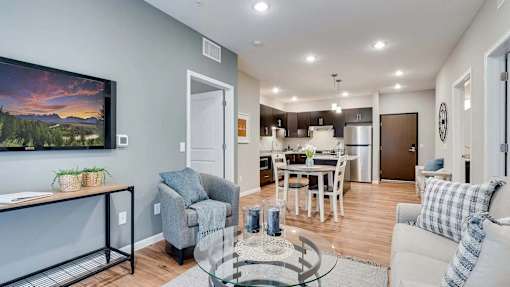 a living room with a couch and a table in front of a kitchen. Circle Pines, MN Lexington Lofts