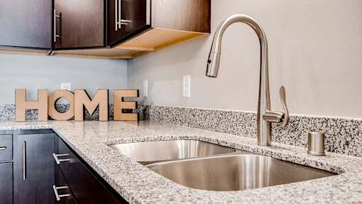 a kitchen with a sink and home letters on the counter. Circle Pines, MN Lexington Lofts