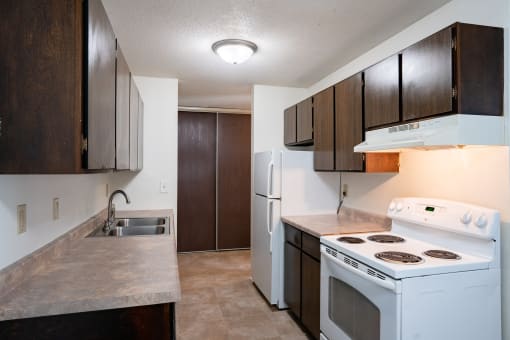 an empty kitchen with white appliances and wooden cabinets. Coon Rapids, MN Robinwood Apartments