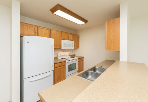 a kitchen with white appliances and wooden cabinets. Fargo, ND Sunrise North