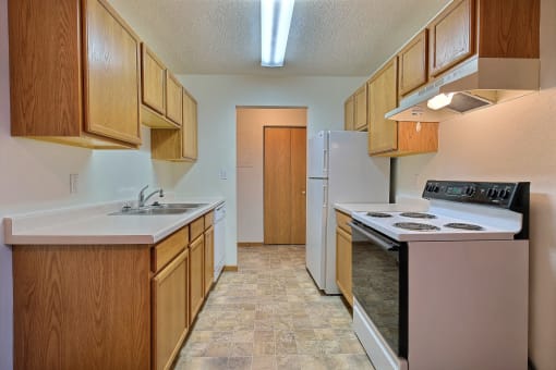 a kitchen with white appliances. Fargo, ND Dakota Manor Apartments