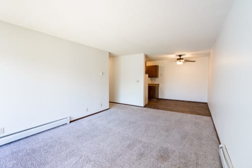 an empty living room with carpet and a ceiling fan.  Eagan, MN Glen Pond Apartments
