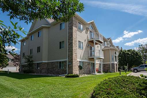 A large, two-story residential building with a stone foundation and a mix of siding and stone exterior.