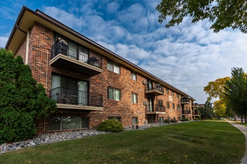 a brick building with three levels and a sidewalk in front. Fargo, ND Emerald Apartments