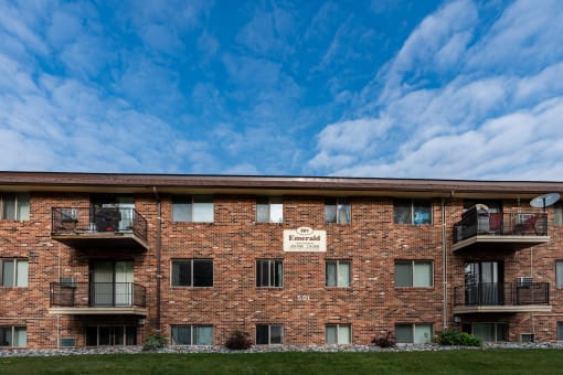 a brick apartment building with balconies and a blue sky. Fargo, ND Emerald Apartments