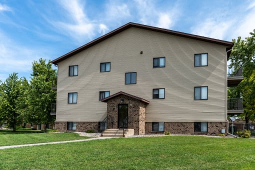 An apartment building with a grassy yard in front of it. Fargo, ND Granger Court Apartments.