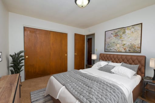 a bedroom with a large bed and a painting on the wall. Fargo, ND North Manor Apartments