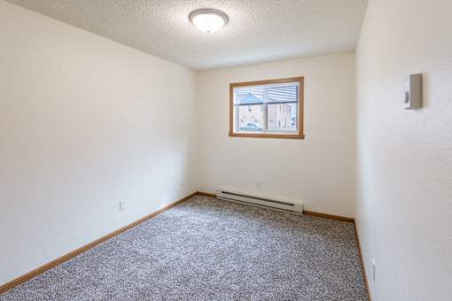 Fargo, ND Patricia Ann Apartments. A bedroom with white walls and carpet