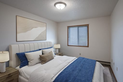 a bedroom with a large bed and a window. Fargo, ND Prairie Park Apartments