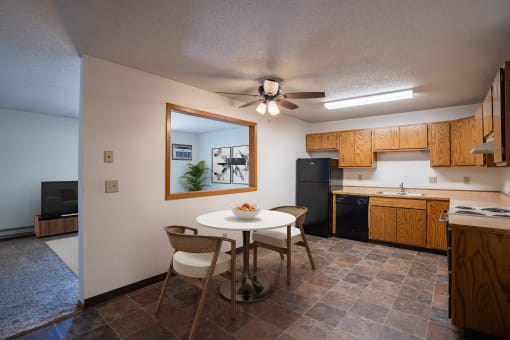 a kitchen and dining area with a white table and chairs. Fargo, ND Southview Village Apartments