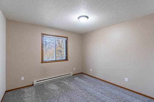 a bedroom with carpet and a window.Fargo, ND Briar Pointe Apartments