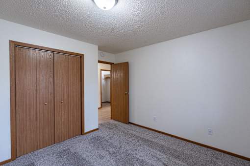 a bedroom with a closet and a door to a hallway. Fargo, ND Briar Pointe Apartments