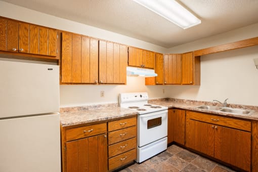 a kitchen with white appliances and wooden cabinets. Fargo, ND Brookfield Apartments