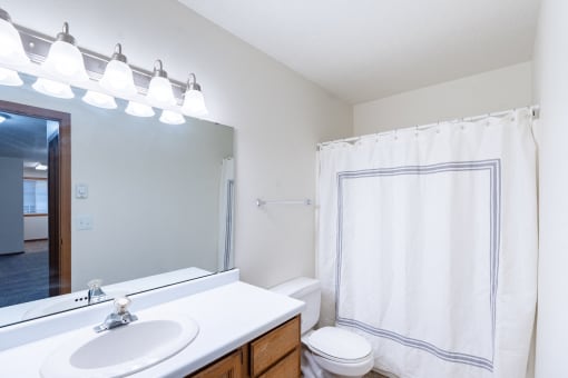a bathroom with a large mirror and a sink and a toilet. Fargo, ND Brownstone Apartments