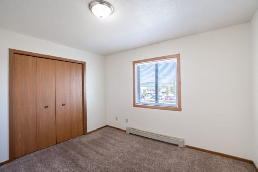 a bedroom with a window and a closet. Fargo, ND Carlton Place Apartments