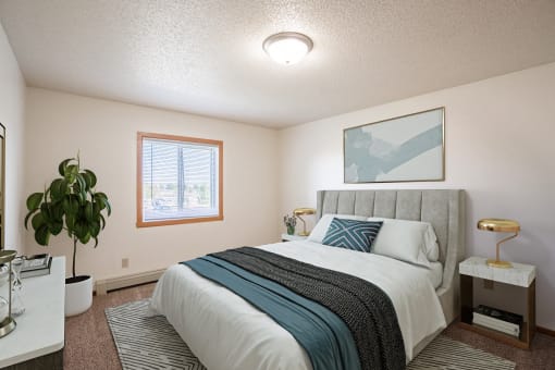 an empty bedroom with a bed and a plant. Fargo, ND Carlton Place Apartments