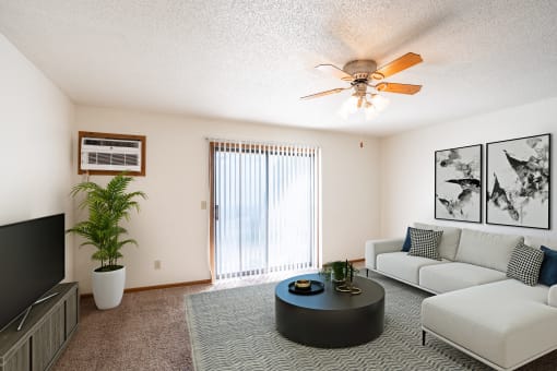 a living room with a couch and a coffee table and a ceiling fan. Fargo, ND Carlton Place Apartments